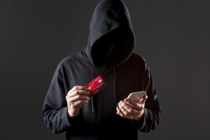 front-view-male-hacker-holding-smartphone-credit-card